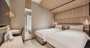 Habitación de hotel con dos camas, un escritorio con silla, televisión y espejo.