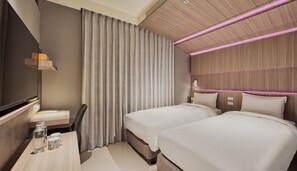 Una habitación de hotel con cama, mesitas de noche, escritorio, silla, espejo y cortina.