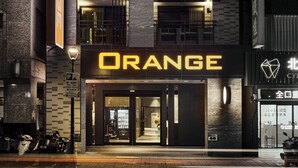 A building with a prominent 'ORANGE' sign, a parking sign, and a storefront with a glass entrance. - Orange Hotel - Hanzhong Taipei (Taipei)
