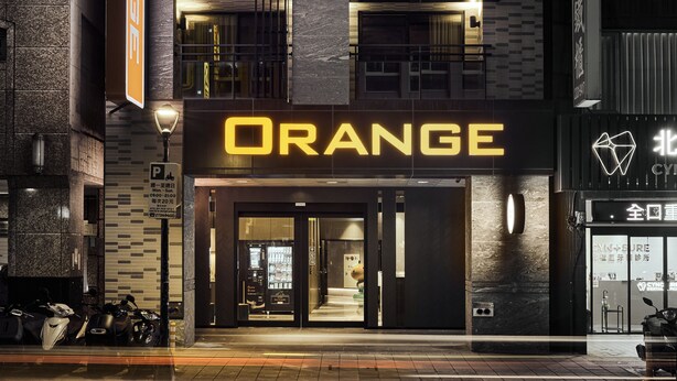 A building with a prominent 'ORANGE' sign, a parking sign, and a storefront with a glass entrance. - Orange Hotel - Hanzhong Taipei (Taipei)