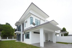 A modern two-story house with a flat roof, large windows, and a covered patio area.