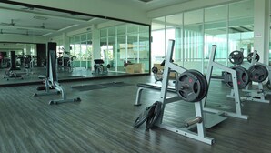Een sportschool met gewichthefapparatuur, spiegels en een groot raam.
