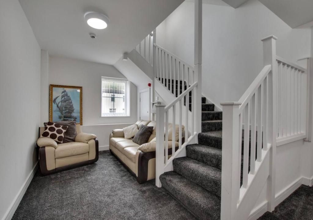 A living room with two sofas, a staircase, and a framed picture on the wall.