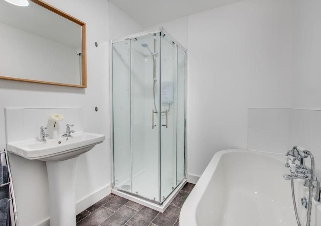 A modern bathroom with a glass-enclosed shower, a white sink, and a bathtub.
