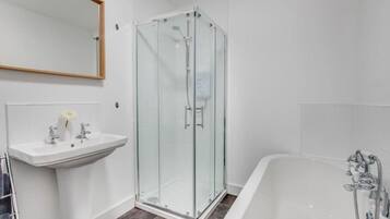 A modern bathroom with a glass-enclosed shower, a white sink, and a bathtub.