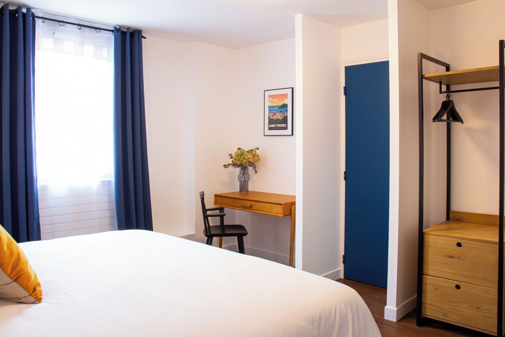 Una camera da letto con un letto, una scrivania, una sedia, uno scaffale e una porta.