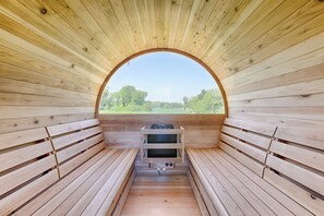 A sauna with wooden benches and a view through an arched opening.