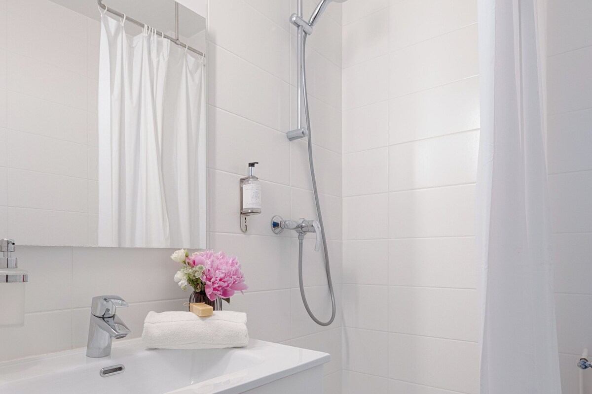 A modern bathroom with a shower, a sink, and a mirror.