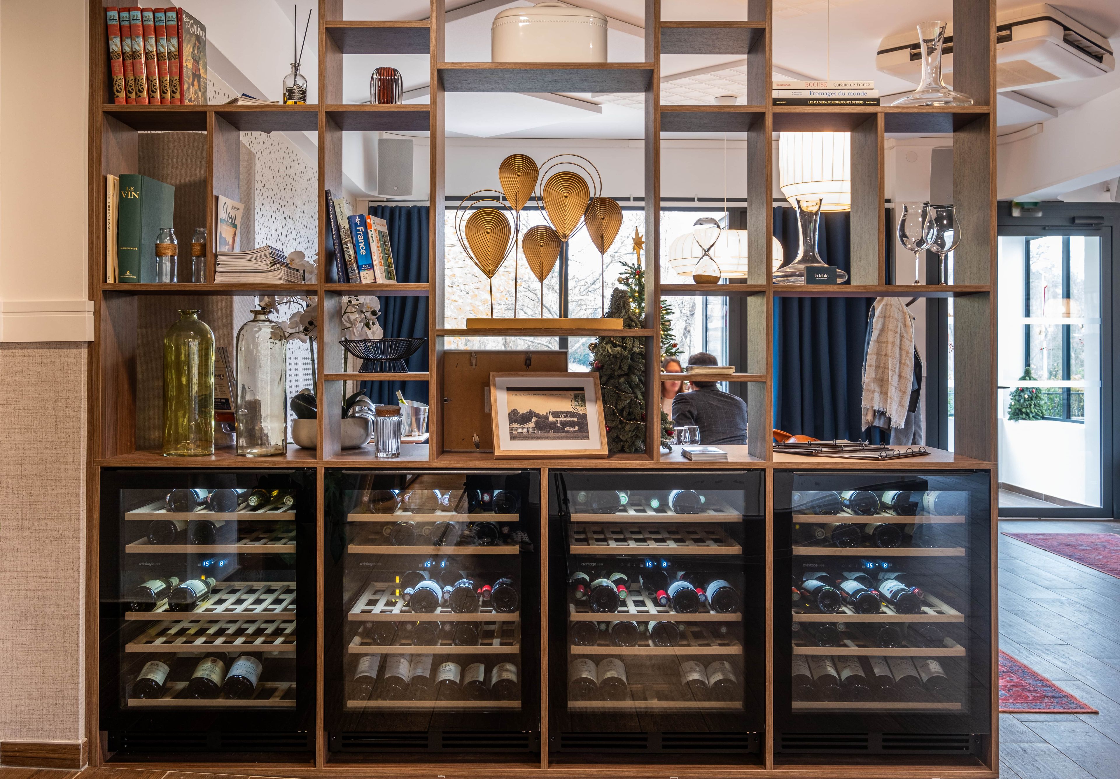 Una bodega con múltiples estanterías para vino, y una variedad de libros y objetos decorativos en repisas.