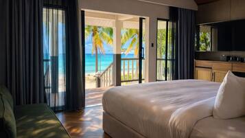 Ein Schlafzimmer mit einem großen Bett, einem Fernseher und Blick auf den Strand.
