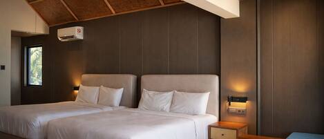 Una habitación de hotel moderna con dos camas, techo de madera y una pequeña mesa.
