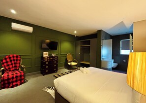 A hotel room with a bed, a chair, a dresser, a television, and a bathroom visible through an open door. - Blix Inn (Stellenbosch)