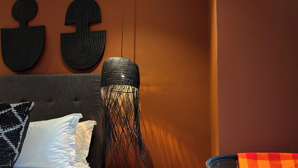 A bed with white bedding, a black lamp, and a checkered chair. - Blix Inn (Stellenbosch)