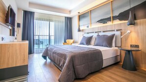 A modern hotel room with a large bed, a desk, a chair, and a view of the outdoors through the window. - Maia Beach Hotel (Aydın)