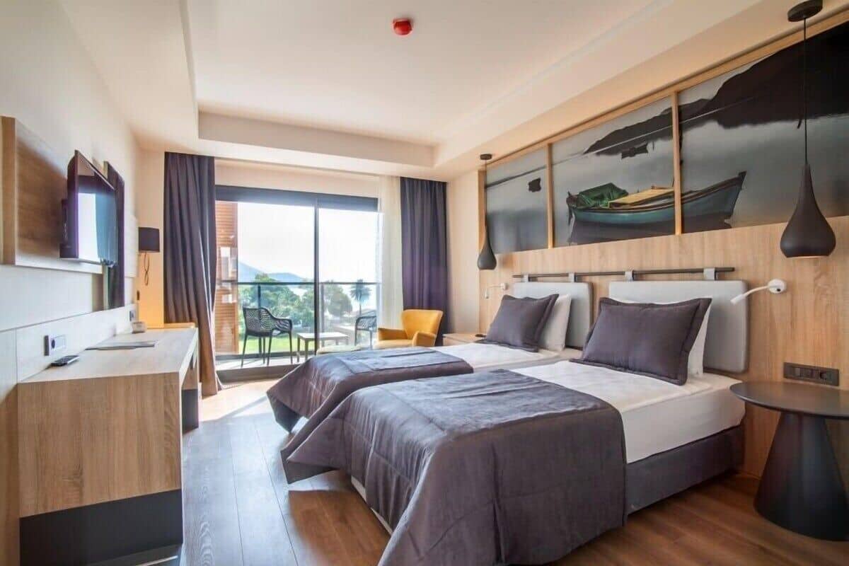 Una habitación de hotel moderna con dos camas, un escritorio y una zona de comedor con vistas.