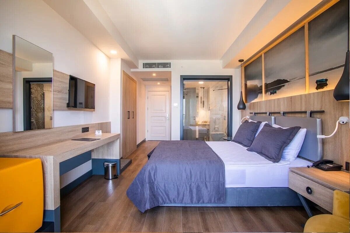 Una habitación de hotel moderna con cama, mesita de noche, espejo y vistas al baño.