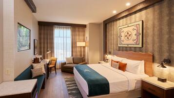 A hotel room with a bed, a desk, a chair, and a window with curtains.
