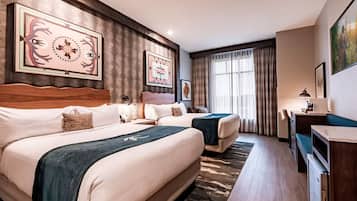 A hotel room with two beds, a desk, and artwork on the walls.