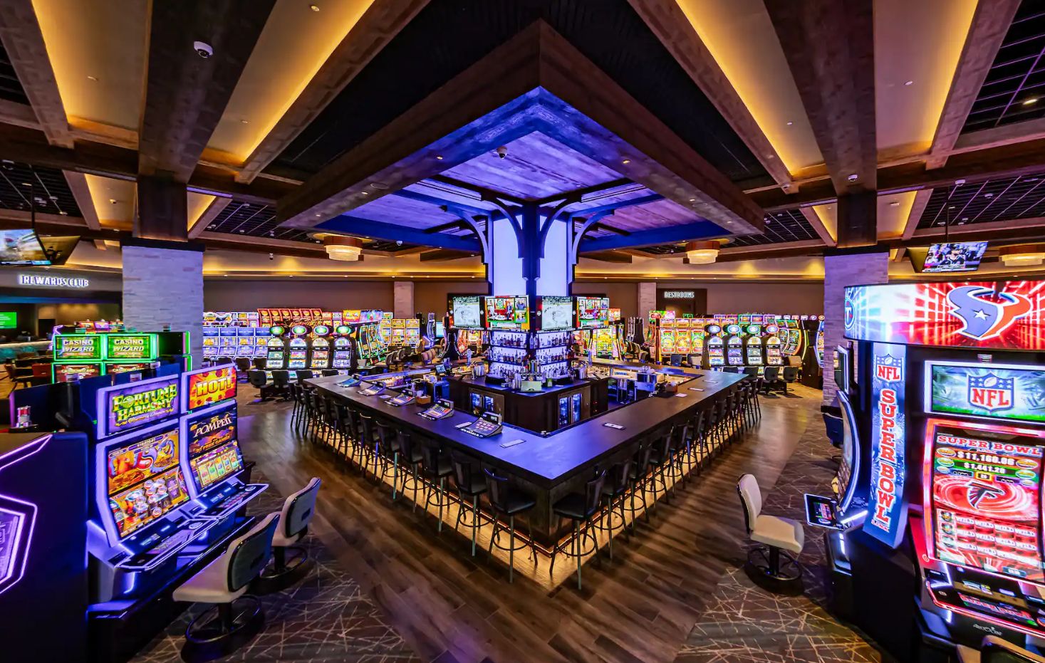 A casino with multiple gaming machines, a bar area, and a sports-themed display.