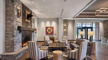 A spacious living area with a stone fireplace, comfortable seating, and a large window providing a view.