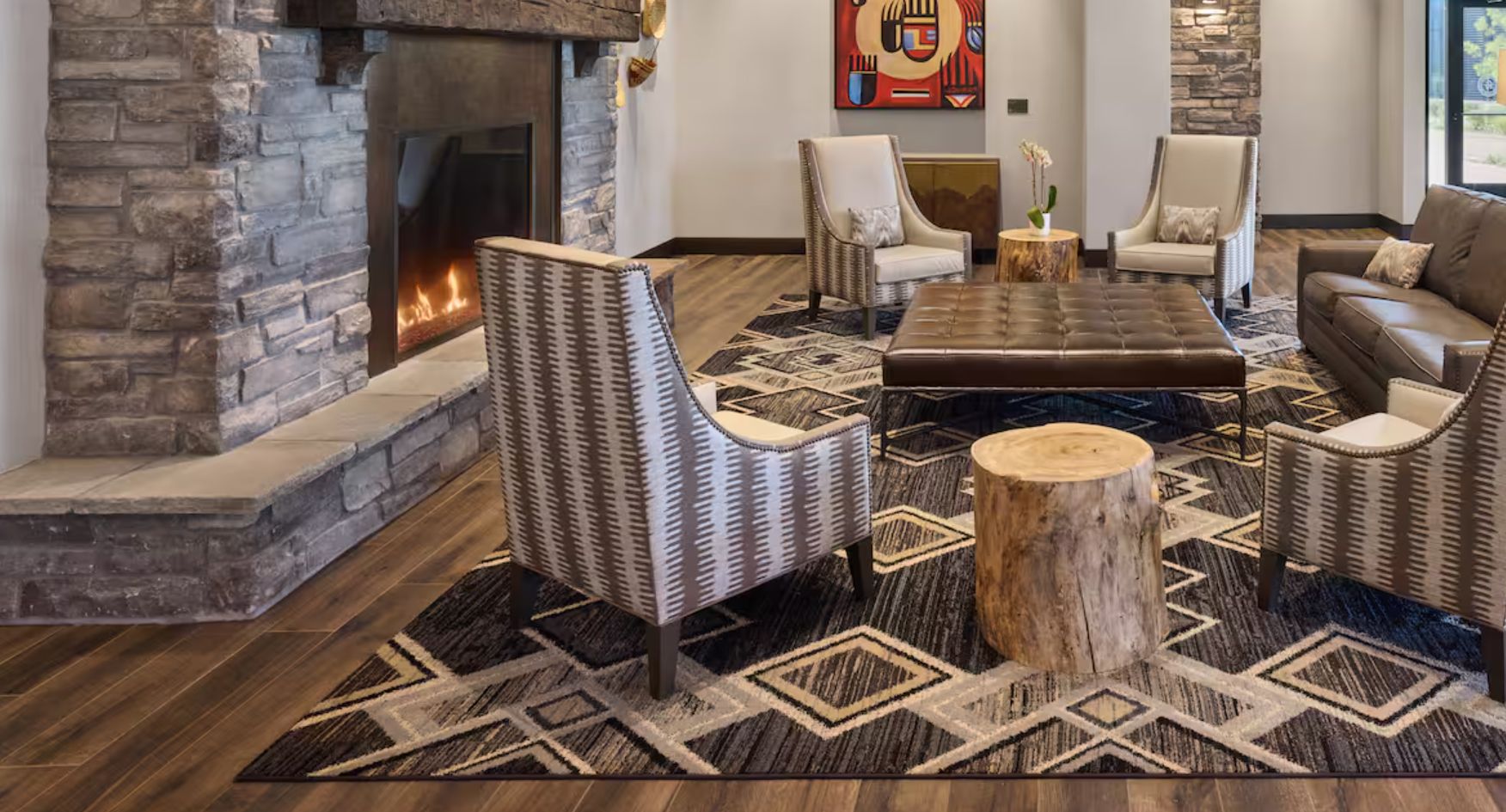 Een woonkamer met een stenen openhaard, leren banken en vloerkleden met een patroon.