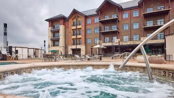 A hotel with a pool area, outdoor seating, and a building with multiple balconies.