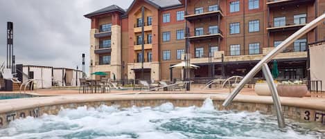A hotel with a pool area, outdoor seating, and a building with multiple balconies.