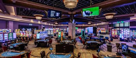 Ein Casino mit mehreren Spieltischen und Spielautomaten.