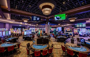 Un casino con varias mesas de juego y máquinas tragamonedas.