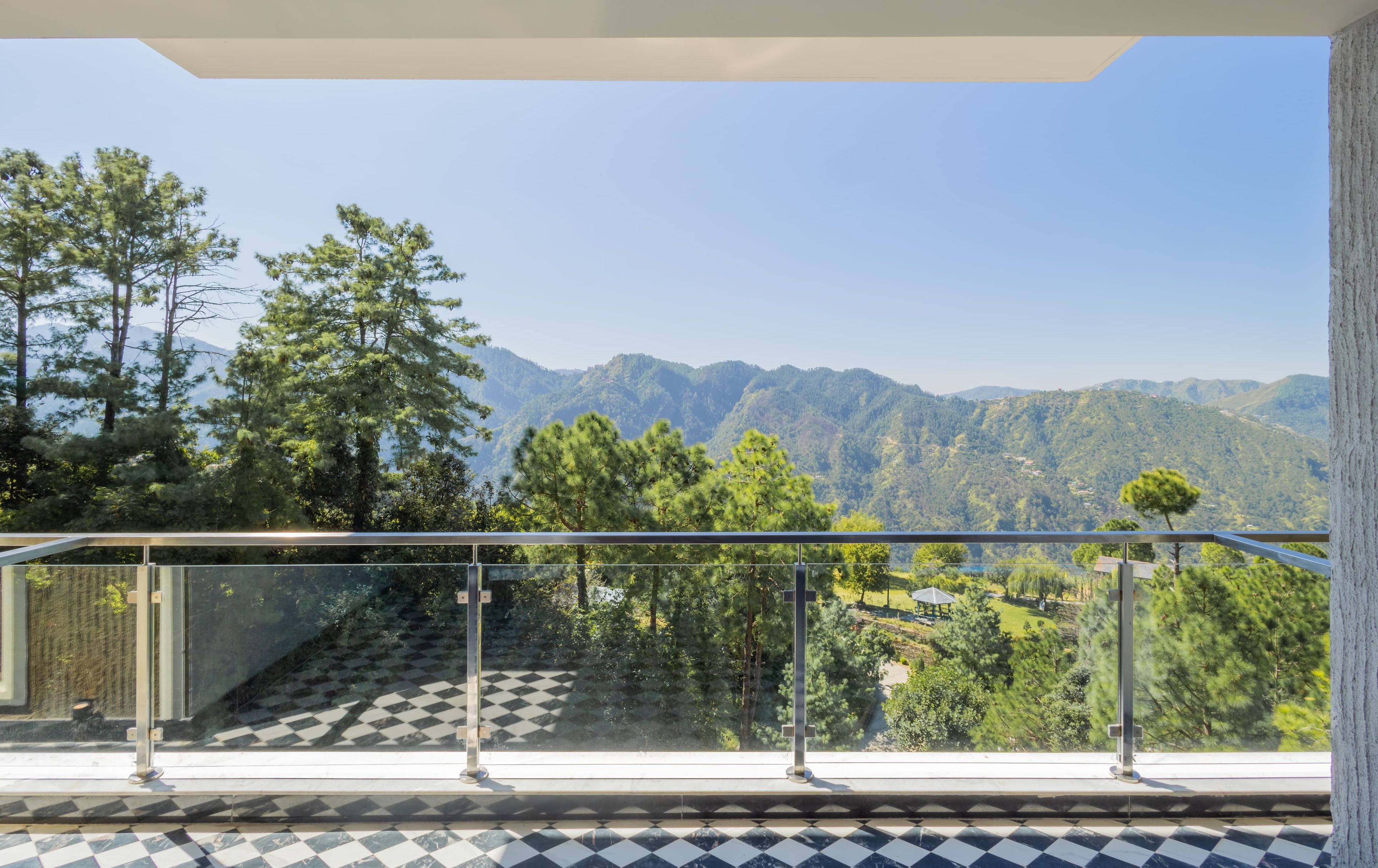 A balcony with a glass railing overlooking a mountainous landscape.