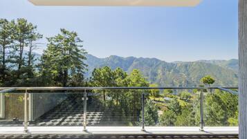 A balcony with a glass railing overlooking a mountainous landscape.