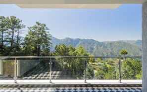 A balcony with a glass railing overlooking a mountainous landscape. - The Manor Sports And Wellness Hotel (Shimla)