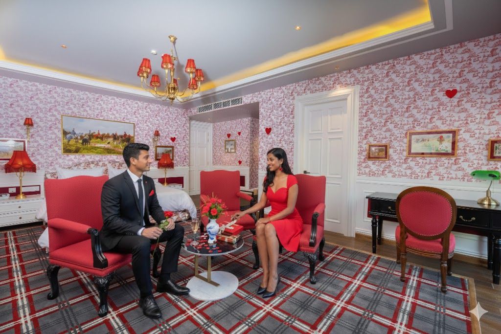 A room with red upholstered chairs, a plaid carpet, and a chandelier.