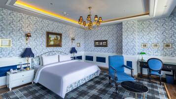 Un dormitorio con una cama, un sillón azul, un escritorio y una araña.