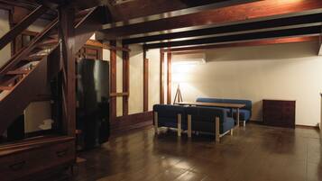 Un'ampia stanza con una scala in legno, un divano blu e un tavolo in legno.