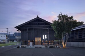 A modern building with a large entrance, a tree in front, and a clear sky. - Bon-yado Uakita Nishimonai (Ugo)