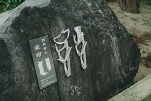 A large rock with carved Chinese characters and a plaque with names.