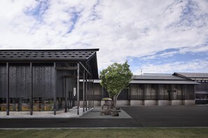 Un bâtiment moderne avec un grand espace ouvert devant, un arbre et un ciel dégagé.