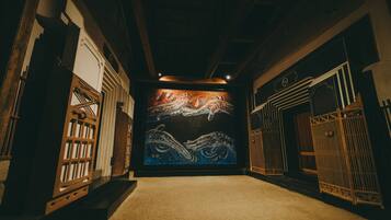 A hallway with a large mural of octopuses on the wall, wooden gates on either side, and a carpeted floor.