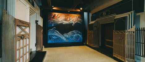 Un pasillo con un mural, puertas de madera y una reja de metal.