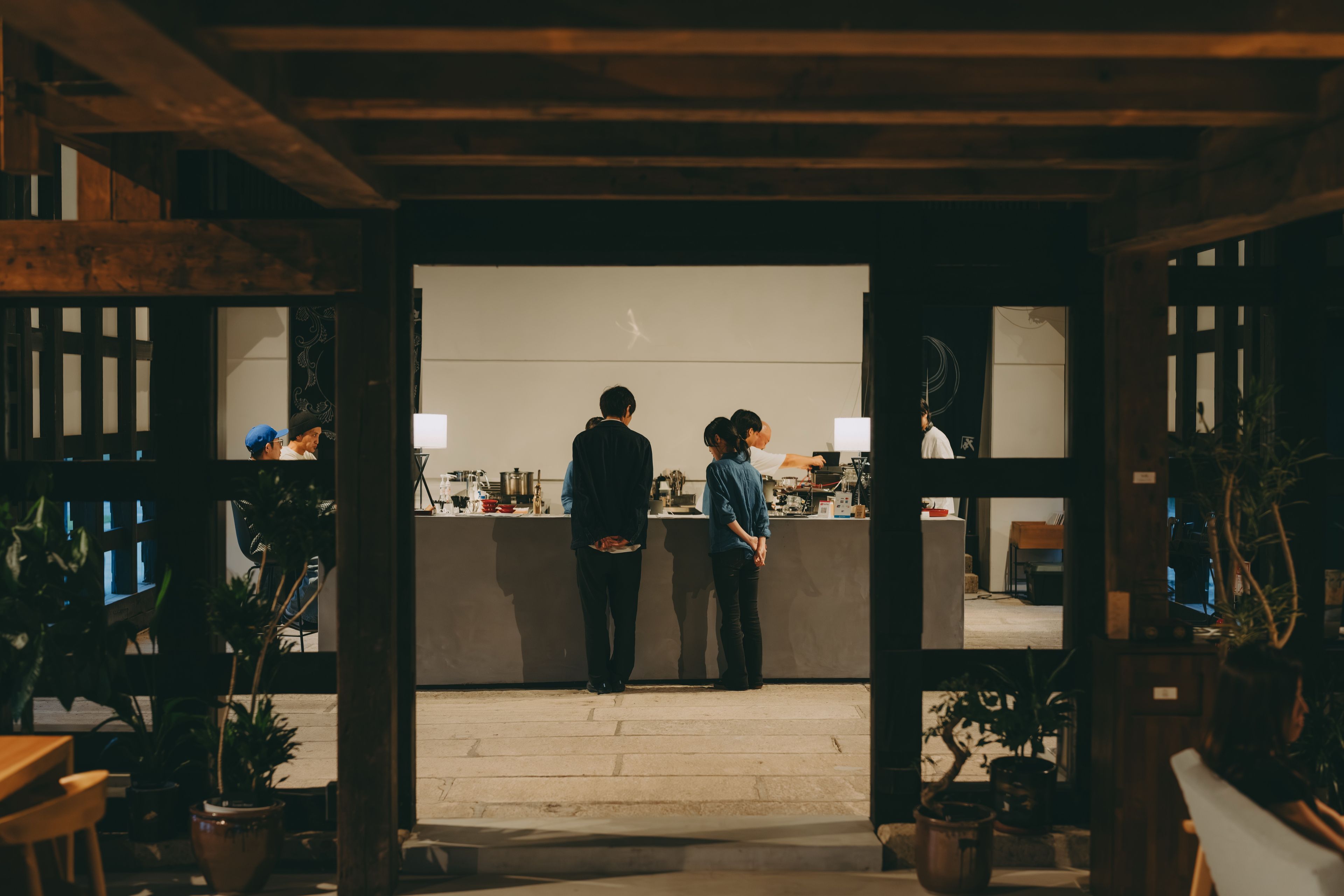 A restaurant with a counter and two people standing at it.