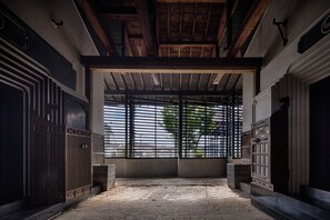 An interior space with a high ceiling, wooden beams, and a large window with metal bars. - Bon-yado Uakita Nishimonai (Ugo)