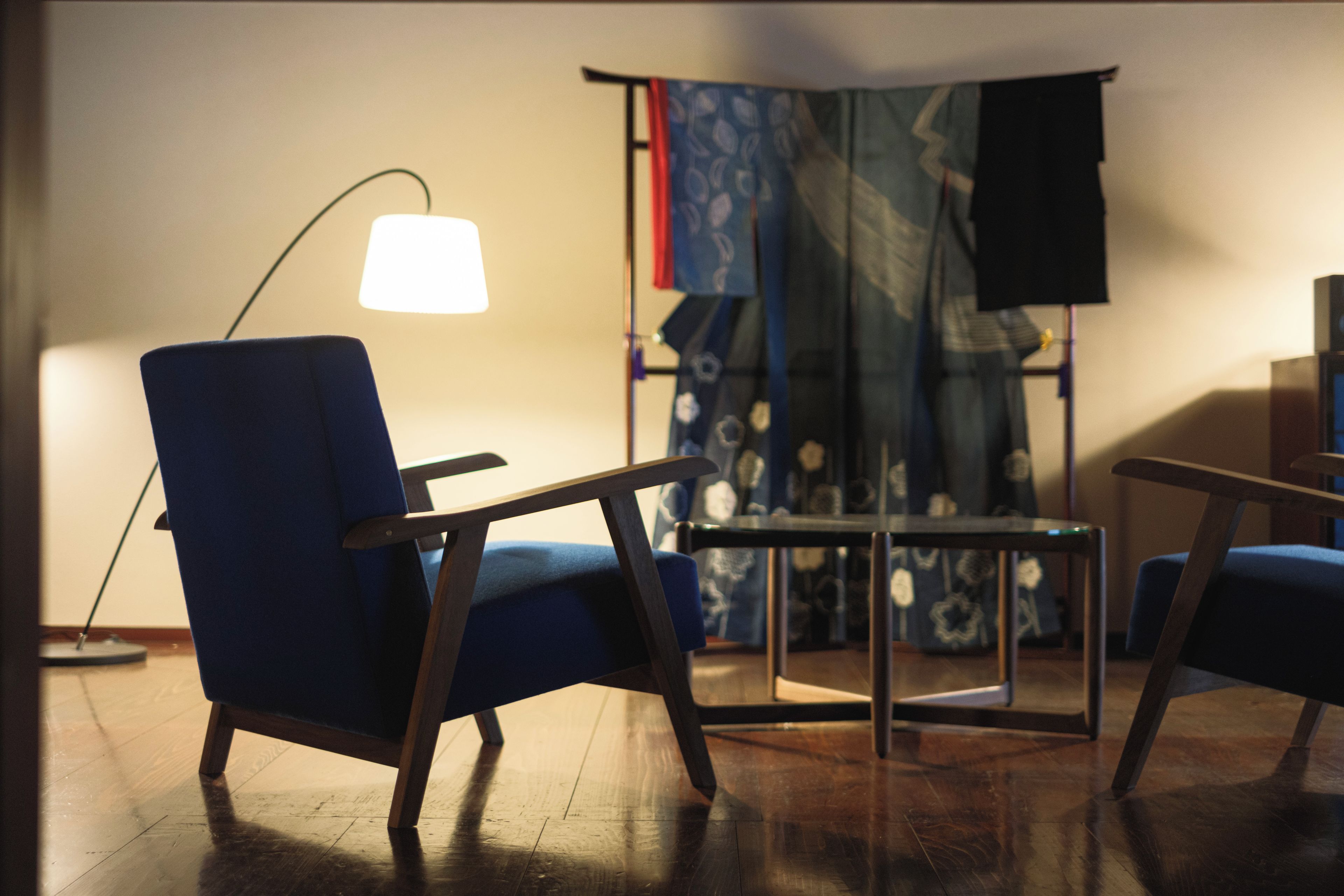 A room with a blue armchair, a small table, and a floor lamp.