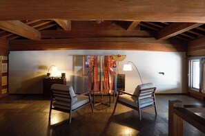 A cozy room with wooden beams, two chairs, a table, and a decorative curtain. - Bon-yado Uakita Nishimonai (Ugo)