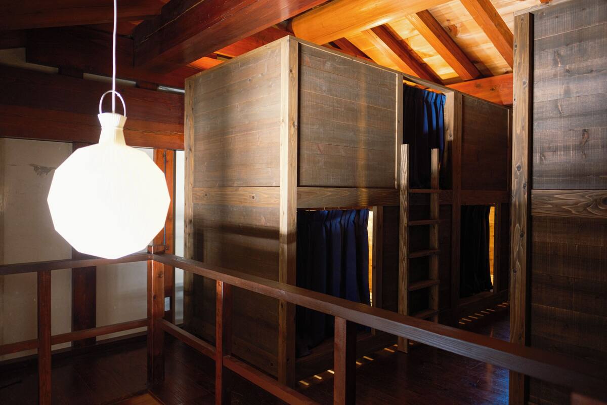 Una habitación con literas de madera, un lámpara colgante y techo de madera.