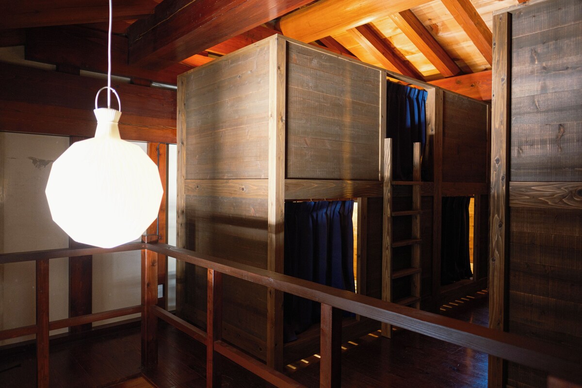 A room with wooden bunk beds, a hanging light fixture, and a wooden ceiling.
