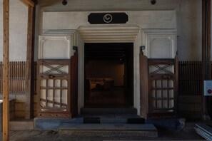 A building entrance with a sign above the door, a staircase leading up to the entrance, and a room visible inside. - Bon-yado Uakita Nishimonai (Ugo)