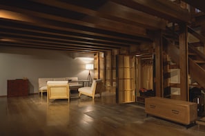 A room with wooden flooring, a sofa, a chair, a lamp, a dresser, and a staircase. - Bon-yado Uakita Nishimonai (Ugo)