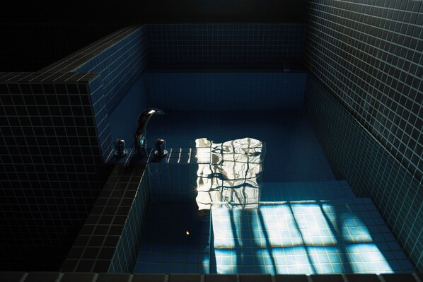 A tiled swimming pool with a faucet and a towel rack.