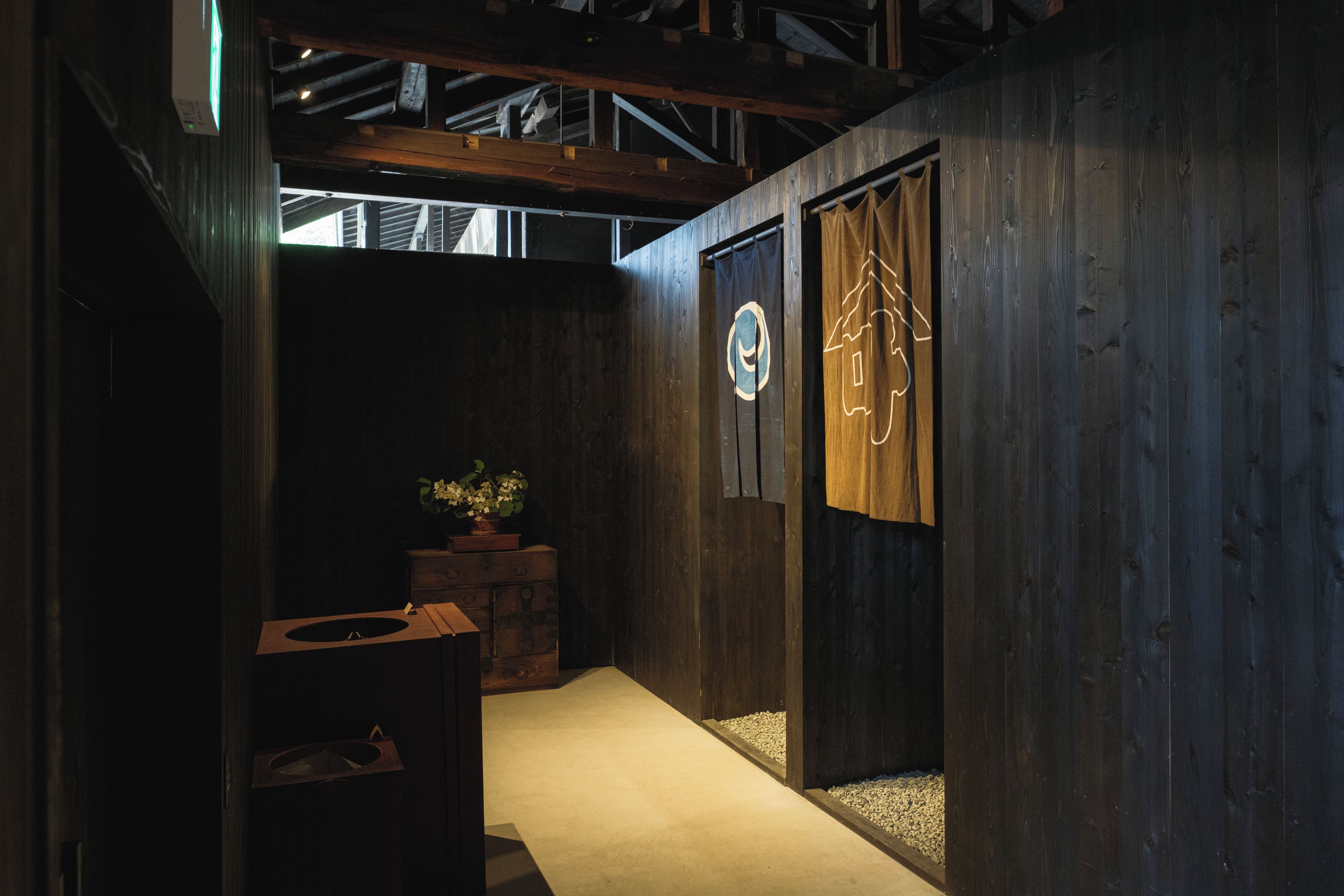 Un pasillo con paredes de madera, una planta en maceta y una puerta con un logo circular.